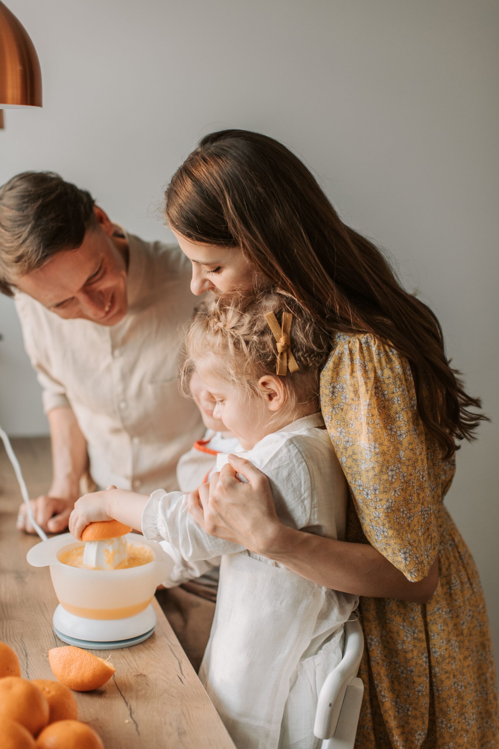 A cheerful family making fresh orange juice in the kitchen during the day.